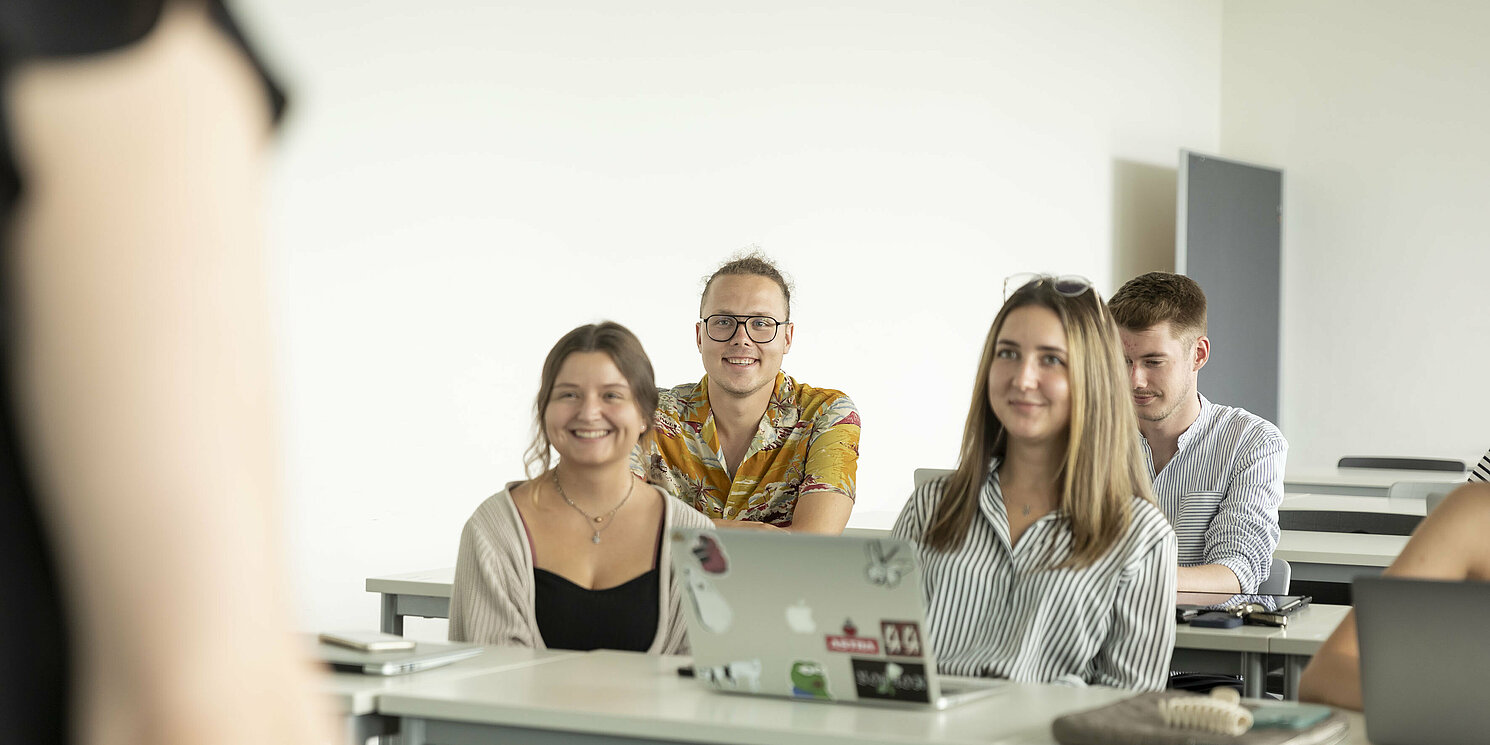 Vier Studierende sitzen in einem Hörsaal.