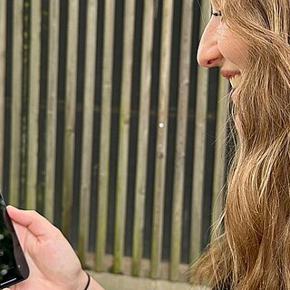 Eine junge Frau schaut auf ihr Smartphone.