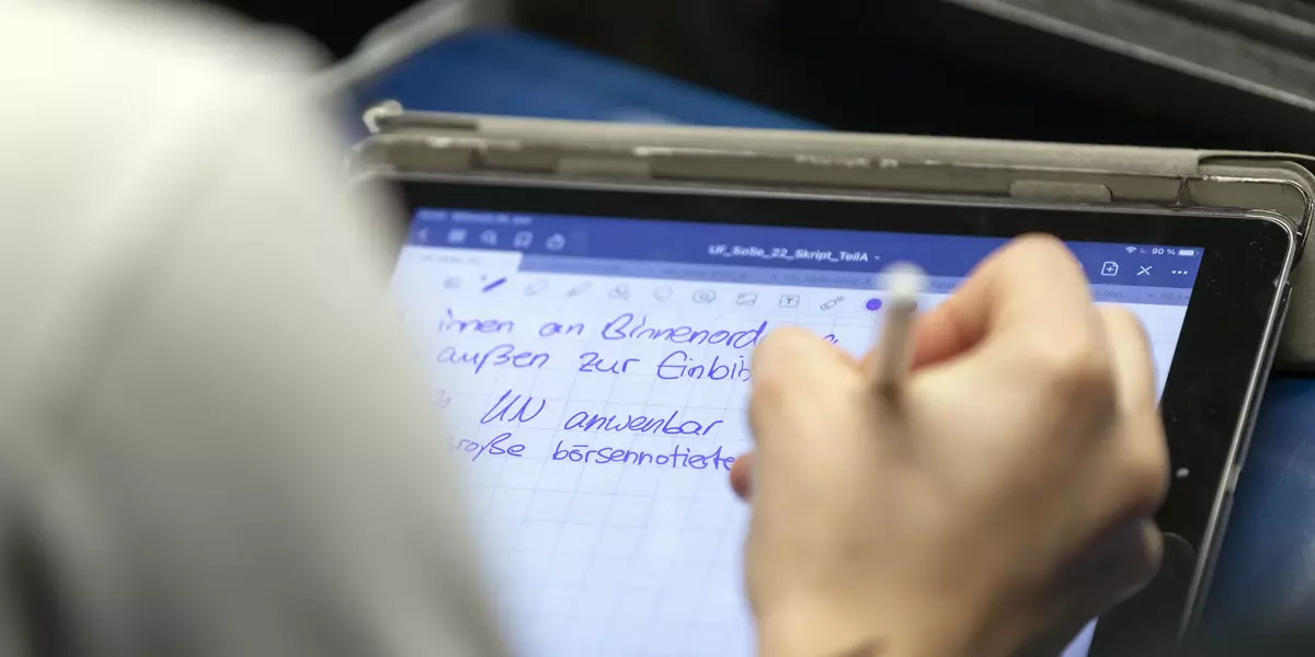 Eine Person bei der man nur die rechte Hand sieht, schreibt auf einem Tablet